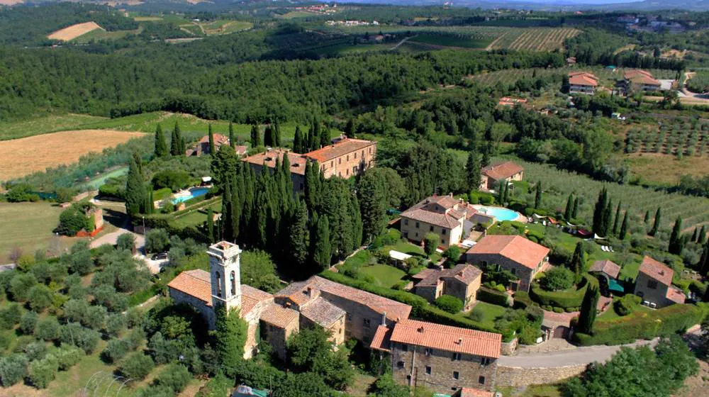 A Tuscan hamlet with cypress trees seen from the air